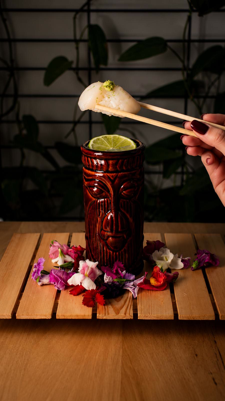 Nigiri sostenido con palillos sobre un cóctel tiki